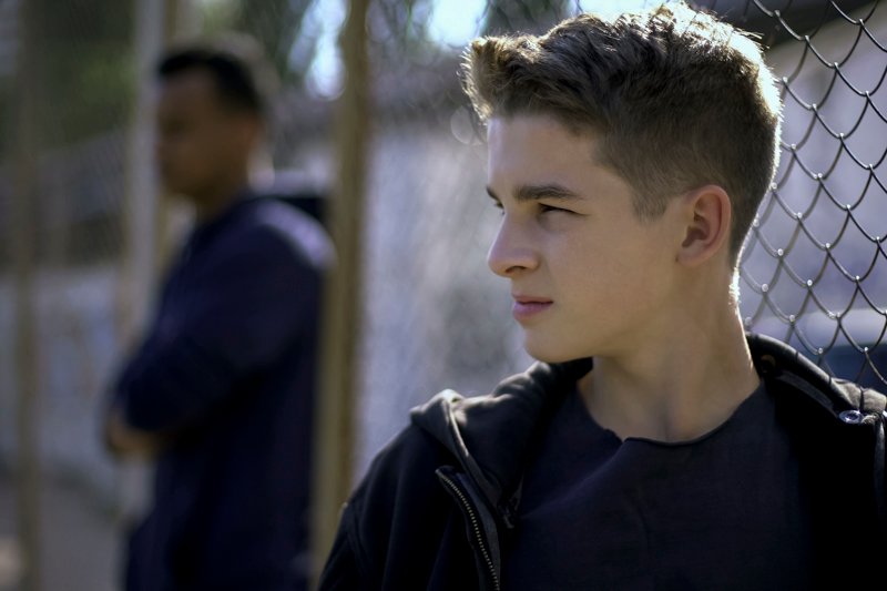 Thoughtful teen boys leaning on metal fence, upset with future,
